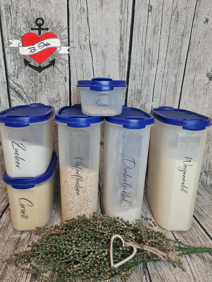 Verschiedene luftdichte Vorratsbehälter mit Etiketten für Zucker, Haferflocken und Dinkelmehl, stilvoll arrangiert mit Blumenakzenten. Entdecke die Möglichkeiten mit easy-sticks und der '138 x Vorratshaltung' Laserdatei.