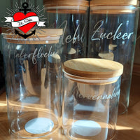 Transparente Aufbewahrungsgläser mit Holzkappen, individuell beschriftet mit Zutaten wie Haferflocken und Zucker. Eine kreative Lösung für Küchenelemente. Entdecke mehr mit der '138 x Vorratshaltung' Laserdatei von easy-sticks.