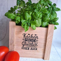 Küchen Dekoration mit Basilikum und einem Holzbehälter, beschriftet mit 'Kochen macht glücklich, essen auch' - Ein kreatives Design von easy-sticks für das Produkt '10 Sprüche für die Küche'.
