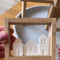 Nahaufnahme von stilvollen weißen Mini-Häusern im Holzrahmen, ideal für kreative Deko, verwendet mit der Silikon Gießform Mini Häuser von easy-sticks.