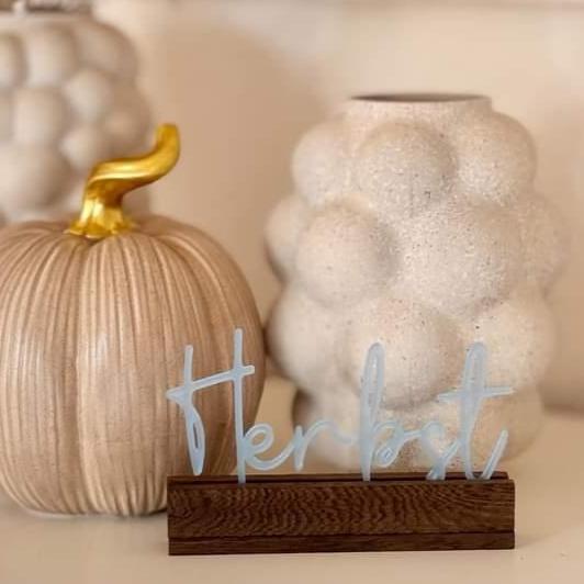 Stylischer Herbstschriftzug von Easy-Sticks Acryl Aufsteller, dekorativ präsentiert neben einem Kürbis und einer Vase.