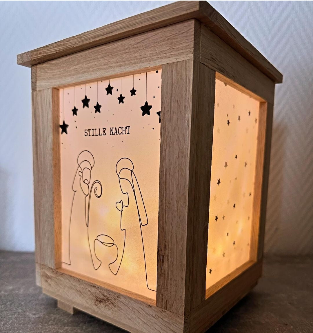 Handgefertigte Krippenlaterne mit dem Titel 'Krippen PDF für deine Krippen Laterne zum Ausdrucken' von easy-sticks. Die Laterne zeigt eine festliche Darstellung mit dem Schriftzug 'STILLE NACHT' und lässt warme Lichter durch die feinen Schnitte scheinen. Ideal für die Weihnachtsdekoration.