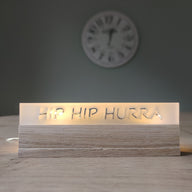 Sapf auf einem Tisch mit dem Schriftzug 'HIP HIP HURRA' aus satiniertem Acryl von Easy-Sticks, ideal für Feierlichkeiten und besondere Anlässe.