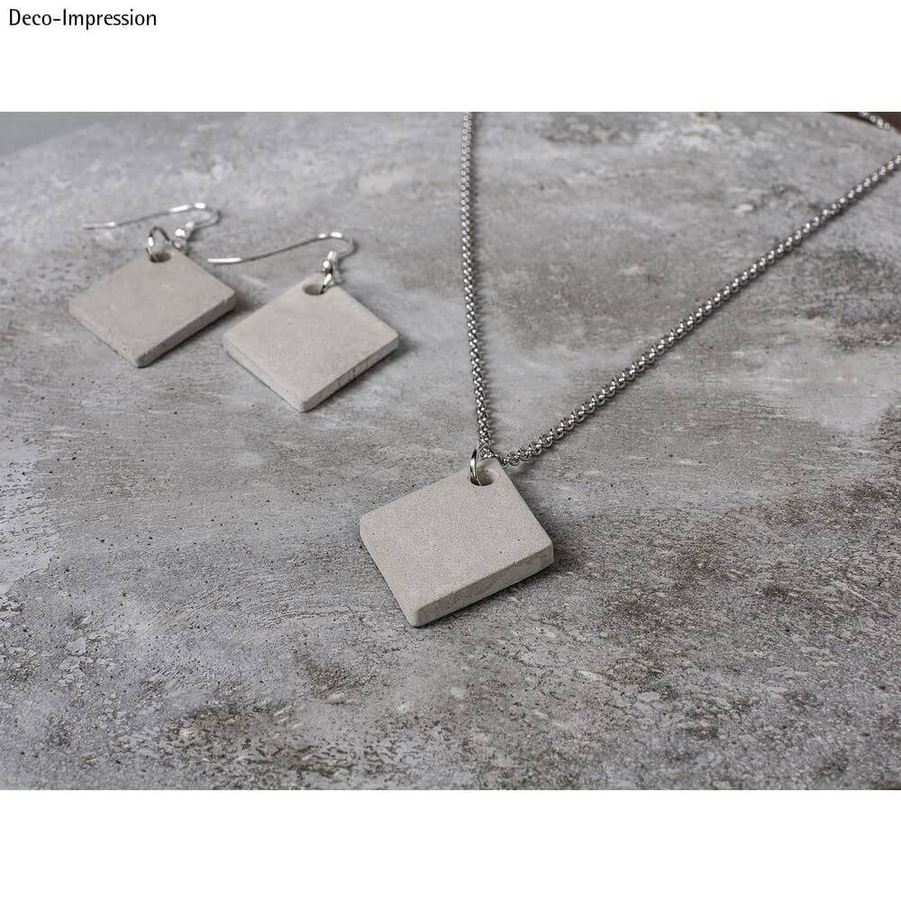 Trendige Schmuckanhänger aus Beton im Rautendesign von easy-sticks. Elegantes graues Set mit Ohrringen und Kettenanhänger präsentiert auf einem Betonuntergrund.