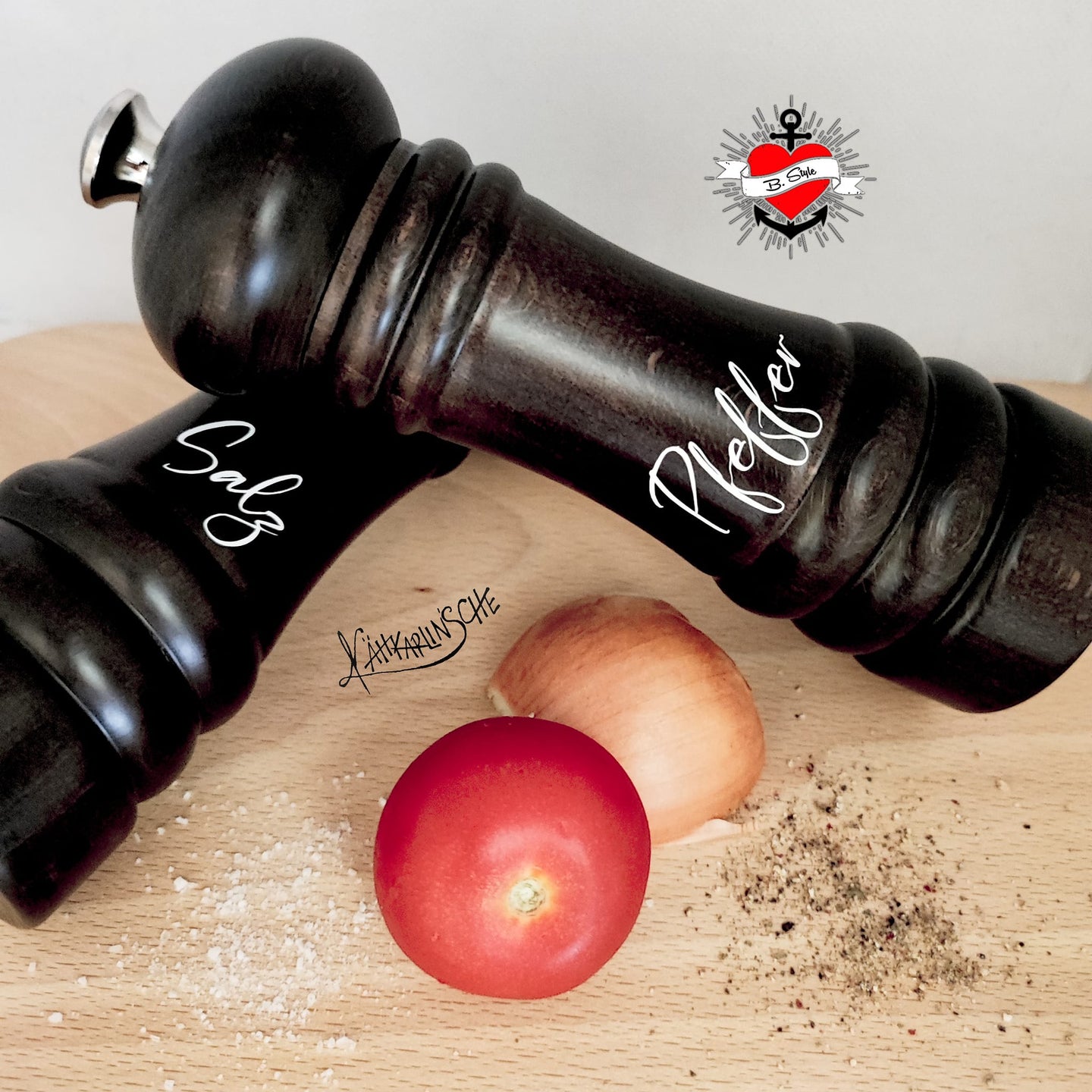 Schwarze Gewürzmühlen für Salz und Pfeffer auf einem Holztisch, gestaltet mit der 89 Gewürze A-Z Laserdatei von easy-sticks.