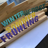 Farbenfrohe Buchstaben Aufsteller mit den Jahreszeiten 'WINTER', 'HERBST', 'SOMMER' und 'FRÜHLING', ideal für saisonale Dekoration mit Easy-Sticks.