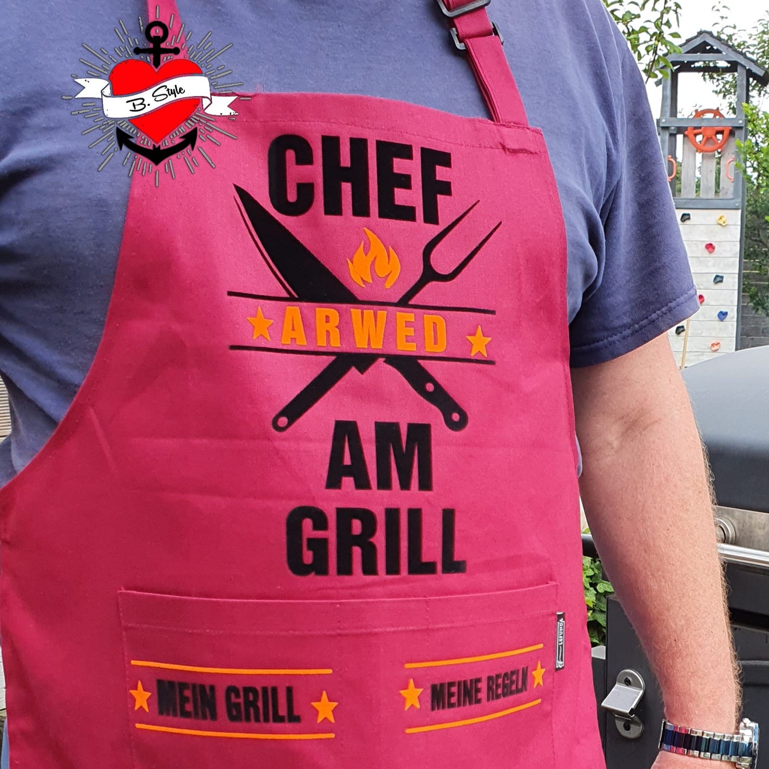 Ein rotes Grill-Schürze mit dem Design 'Chef am Grill' von easy-sticks, perfekt für Grillliebhaber, die ihre Leidenschaft für das Grillen zeigen möchten.