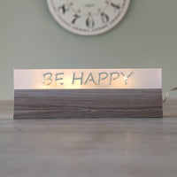 Eleganter Acryl-Easy-Stick 'BE HAPPY' von Easy-Sticks, leuchtet warm auf einem Tisch und schafft eine einladende Atmosphäre.