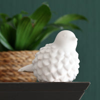 Silikonform - Vogel von Easy-Sticks, eine detailreiche, weiße Vogelskulptur auf einem Regal, umgeben von grünen Pflanzen im Hintergrund.