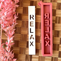 Easy-Sticks Silikonform "Relax" mit einzigartigen Gießformen, die für kreative Windlichter und Lichthäuser verwendet werden können. Die Abbildung zeigt die Silikonform in Pink neben einer abgedruckten Form des Schriftzugs "RELAX" in Weiß, perfekt für individuelle Dekorationen.