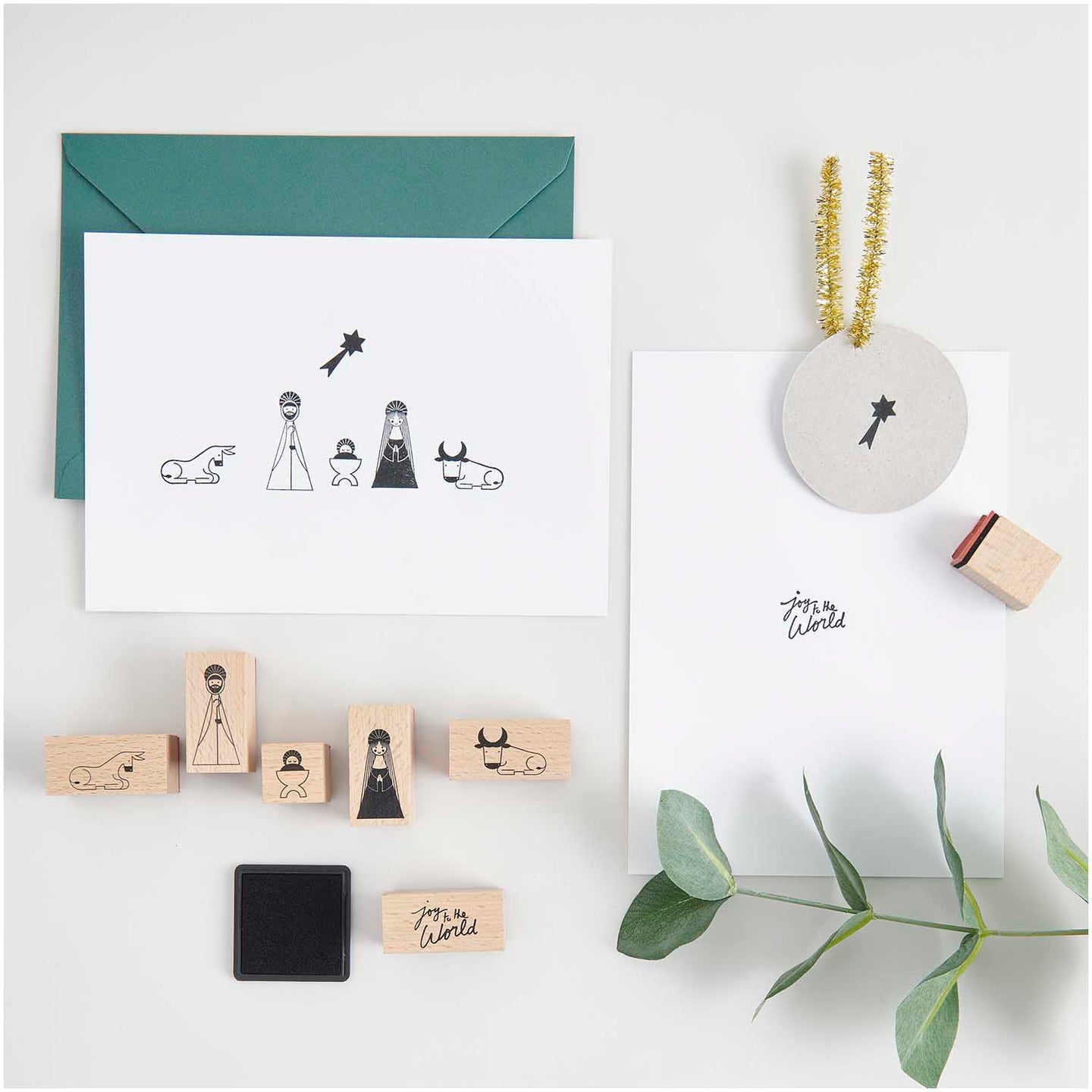 Das Stempelset "Krippe" von easy-sticks, bestehend aus 7 handgefertigten Stempeln, die die Weihnachtsgeschichte darstellen. Die Abbildung zeigt eine kreative Anordnung der Stempel, die Figuren wie Maria, Joseph, Ochse, Esel und einen Stern umfasst, zusammen mit Weihnachtskarten und einem Stempelkissen.