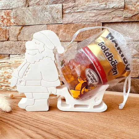 Weihnachtsmann mit Schlitten Silikonform von easy-sticks, präsentiert mit einer Tüte gefüllter Süßigkeiten für festliche Dekorationen.