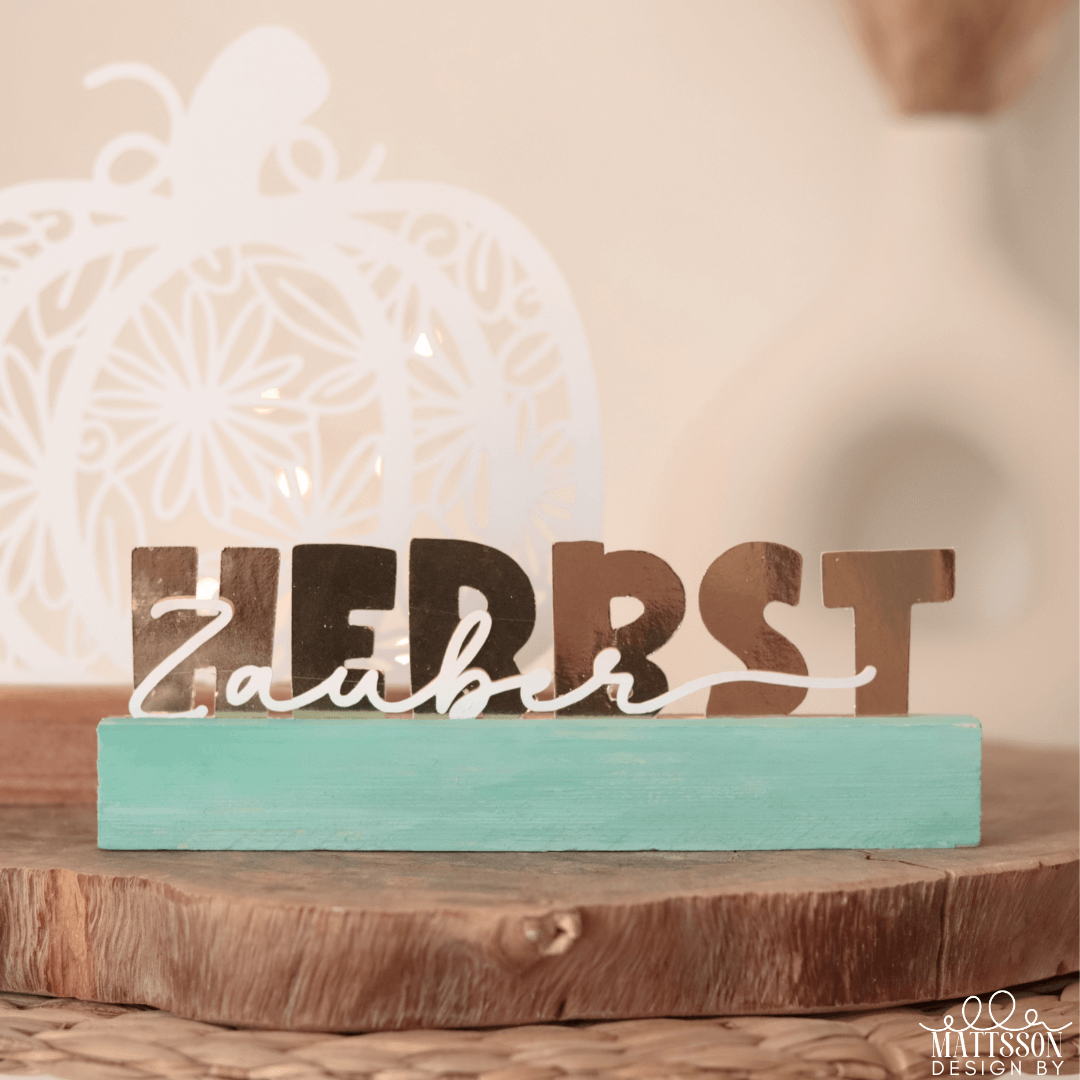 Herbst Aufsteller von easy-sticks, genannt 'Herbst - Zauber, Zeit, Liebe'. Das Bild zeigt einen stilvollen Schriftzug in Brauntönen, auf einem farbigen Holzsockel, ideal für Herbst-Dekorationen und DIY-Projekte.