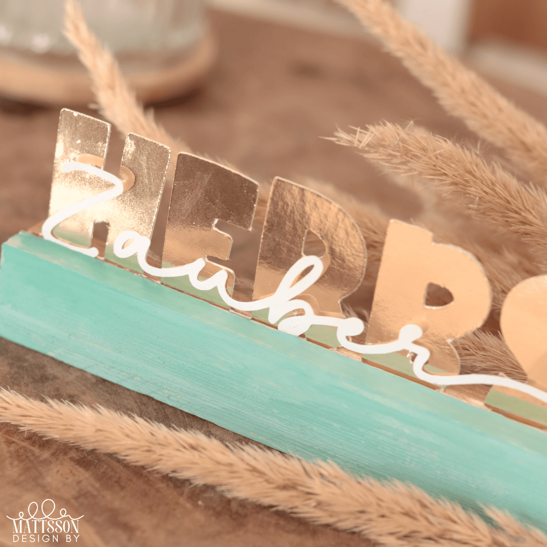 Detailaufnahme des Herbst Aufstellers von easy-sticks mit dem Titel 'Herbst - Zauber, Zeit, Liebe'. Die goldenen Buchstaben auf dem blauen Sockel prägen eine warme Herbststimmung, perfekt für kreative Bastelideen.