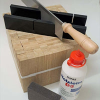 Easy-Sticks 4.0 Starter Set von Easy-Sticks mit Säge, Holzleim und Schleifschwamm auf einem stabilen Holzblock. Ideal für kreative Bastelprojekte und DIY-Anwendungen.