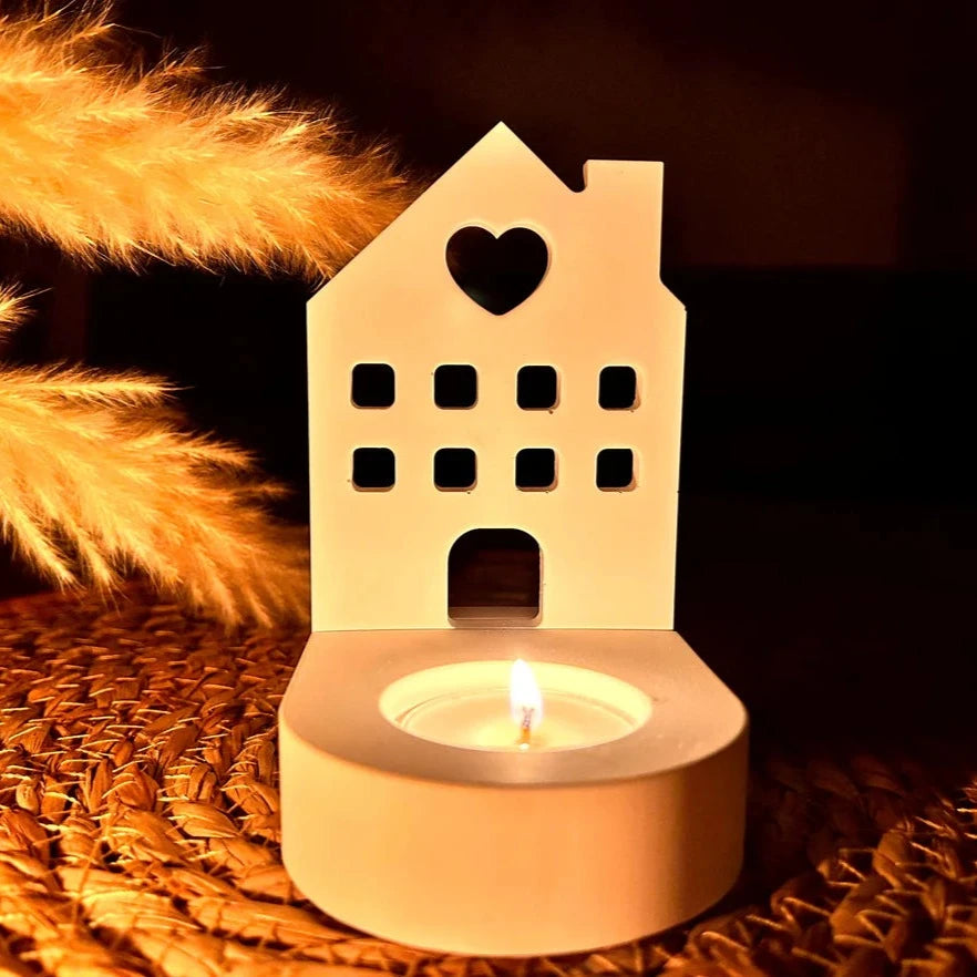 Ein stilvoller Teelichthalter in Form eines Hauses mit Herz von Easy-Sticks, beleuchtet von einer Kerze, bringt eine warme Atmosphäre in jeden Raum. Ideal für romantische Abende.
