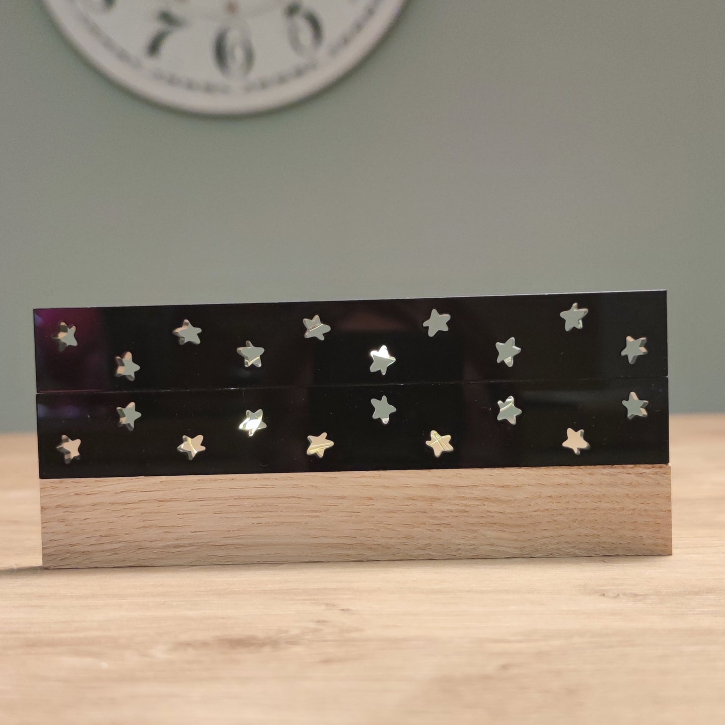 Stylische Acryl-Streifen von Easy-Sticks mit glänzender schwarzer Oberfläche und Sternen, die durch eine Holzunterlage unterstützt werden. Perfekt für kreative Lichtakzente und stilvolle Inneneinrichtungen.
