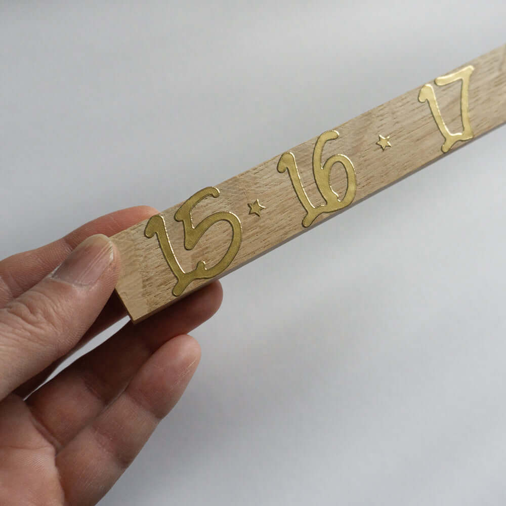 Nahaufnahme eines Adventszahlen Stickers mit den Zahlen 15, 16 und 17 in glänzendem Gold, gehalten in der Hand. Perfekt zur individuellen Gestaltung von Adventskalendern mit easy-sticks.