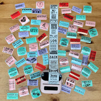 Bunte Aufkleber mit kreativen Sprüchen auf einem Holzuntergrund, ideal für DIY-Projekte. 100 Sticker zum Ausdrucken von easy-sticks.