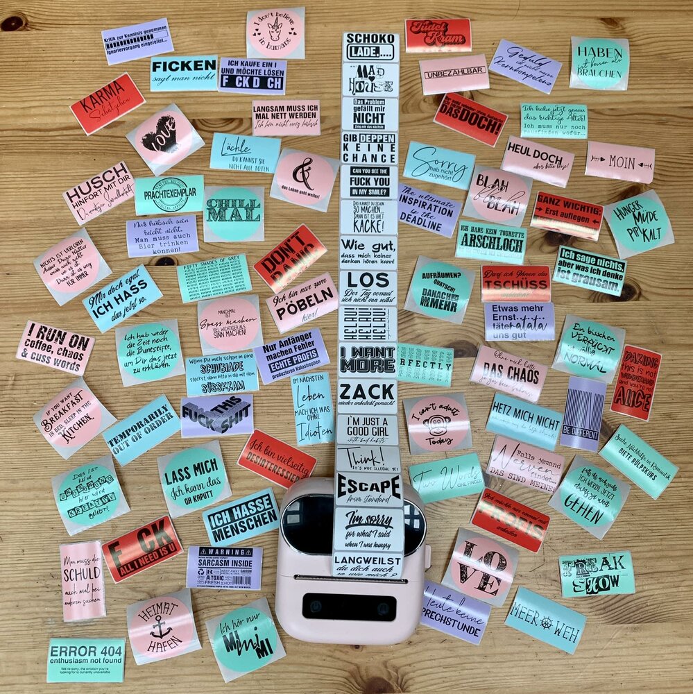 Bunte Aufkleber mit kreativen Sprüchen auf einem Holzuntergrund, ideal für DIY-Projekte. 100 Sticker zum Ausdrucken von easy-sticks.