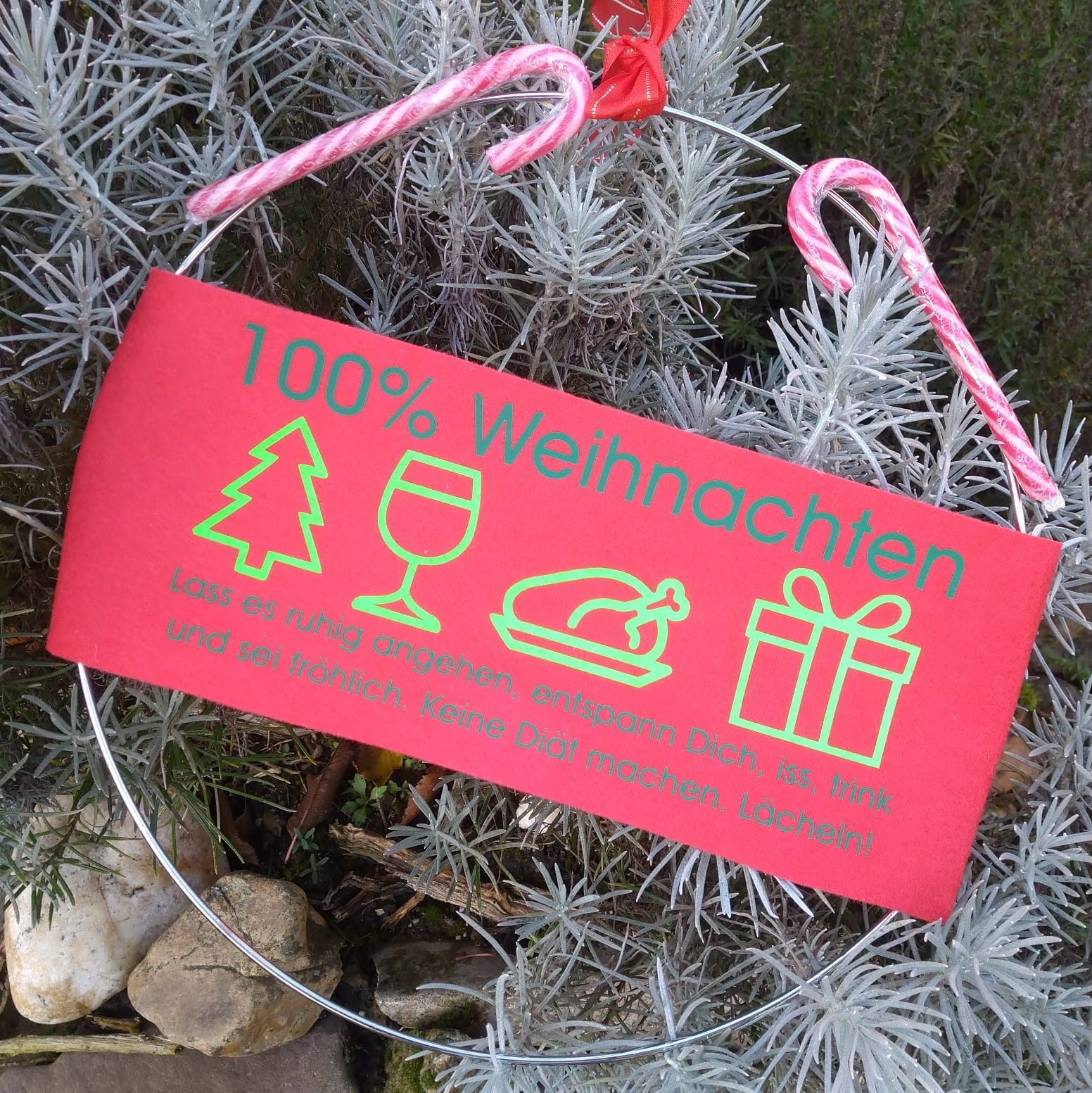 Bunte Dekoration mit der Aufschrift '100% Weihnachten', umgeben von Tannenzweigen; perfekt für festliche Bastelprojekte von easy-sticks.