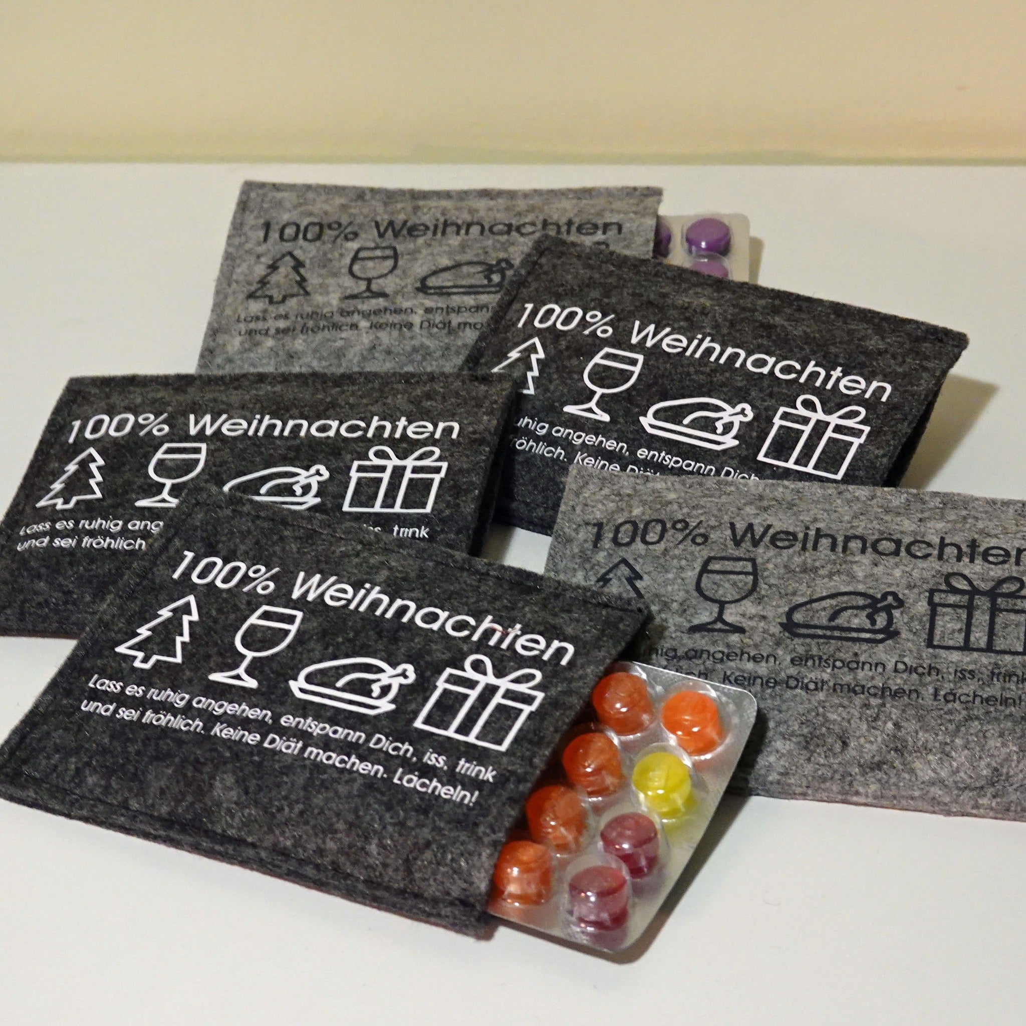 Vielseitige kreative Projekte mit der 100% Weihnachten Plotterdatei von easy-sticks, dargestellt durch stilvolle graue Filzartikel, die festliche Symbole und Schriften zeigen.