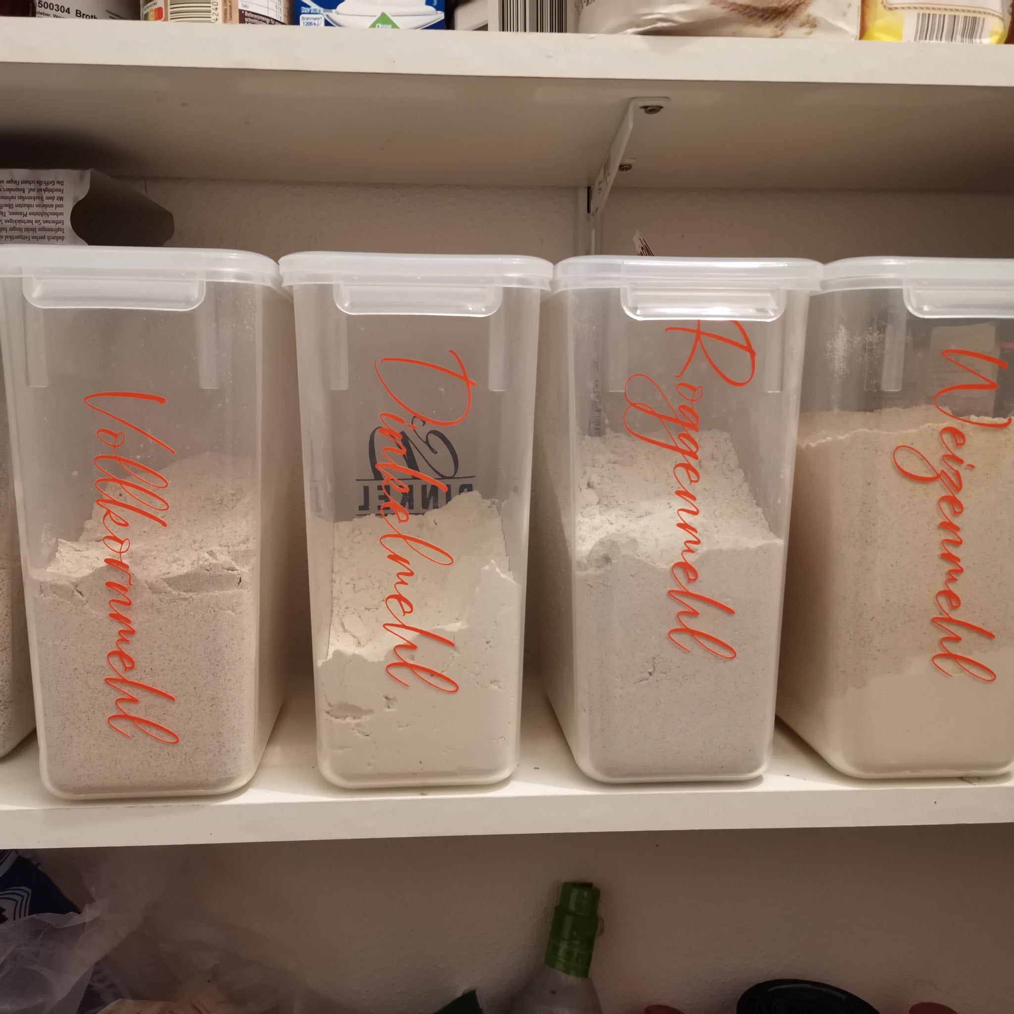 Vier durchsichtige Mehldosen in einer Küchenschrankanordnung, klar beschriftet für Vollkorn-, Dinkel- und Roggenmehl. Ein modernes Designkonzept von easy-sticks, erhältlich in der '138 x Vorratshaltung' Laserdatei.