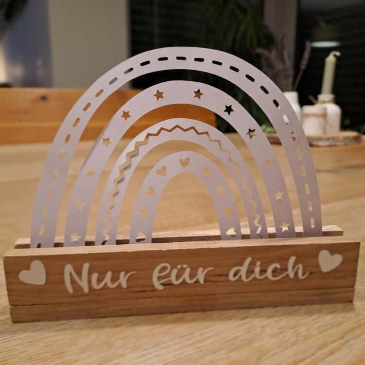 Wunderschöne Holzdekoration mit einem weißen Regenbogen von easy-sticks, inspiriert durch die Regenbogen Plotter Datei, ideal für festliche Anlässe.