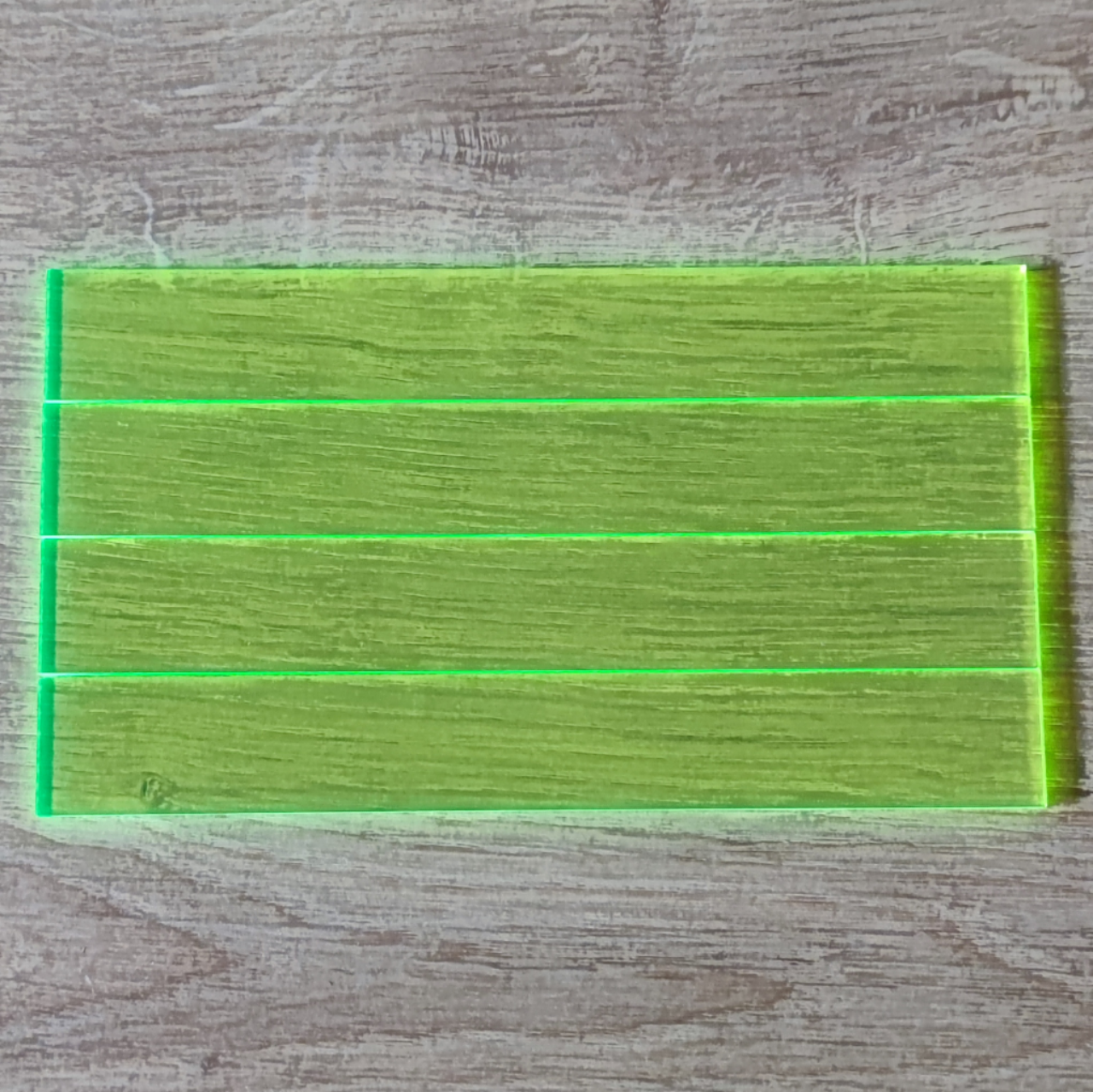 Easy-Sticks Acryl Grün - 4 Stück - 16 cm Länge auf einem Holzuntergrund, Frontansicht der transparenten und fluoreszierenden Acrylplatten von Easy-Sticks.