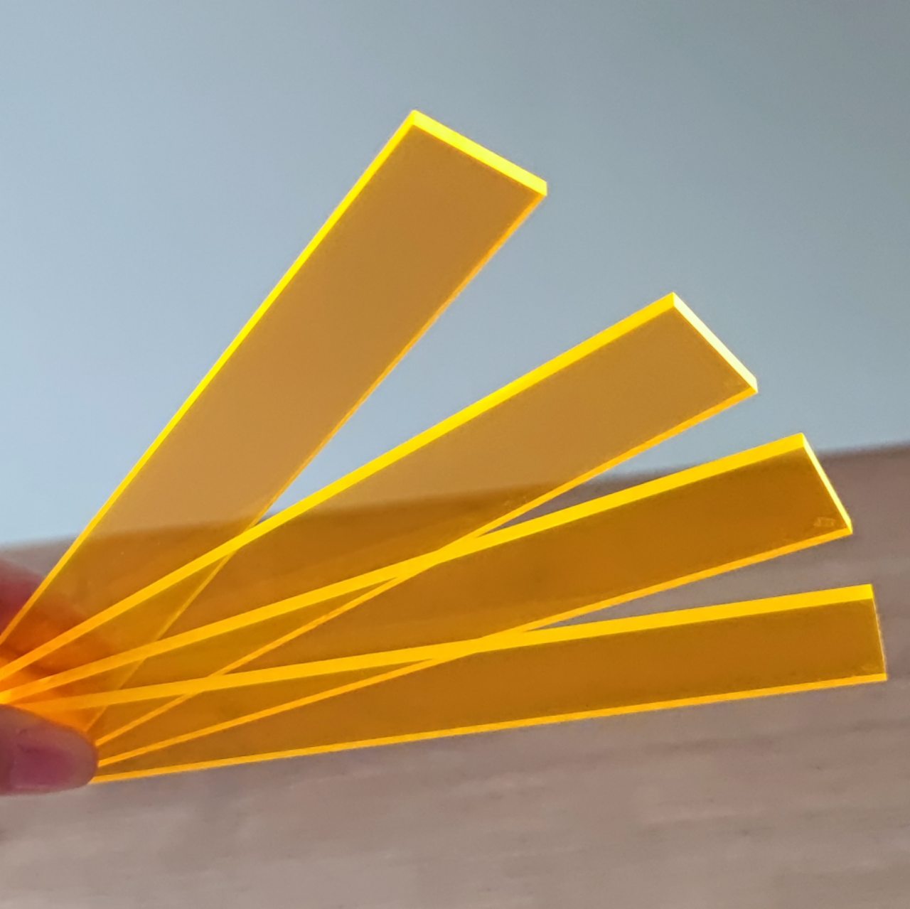 Hand mit leuchtend orangefarbenen Easy-Sticks Acryl – 4 Stück – 16 cm Länge, die ideal für kreative Bastelprojekte sind.