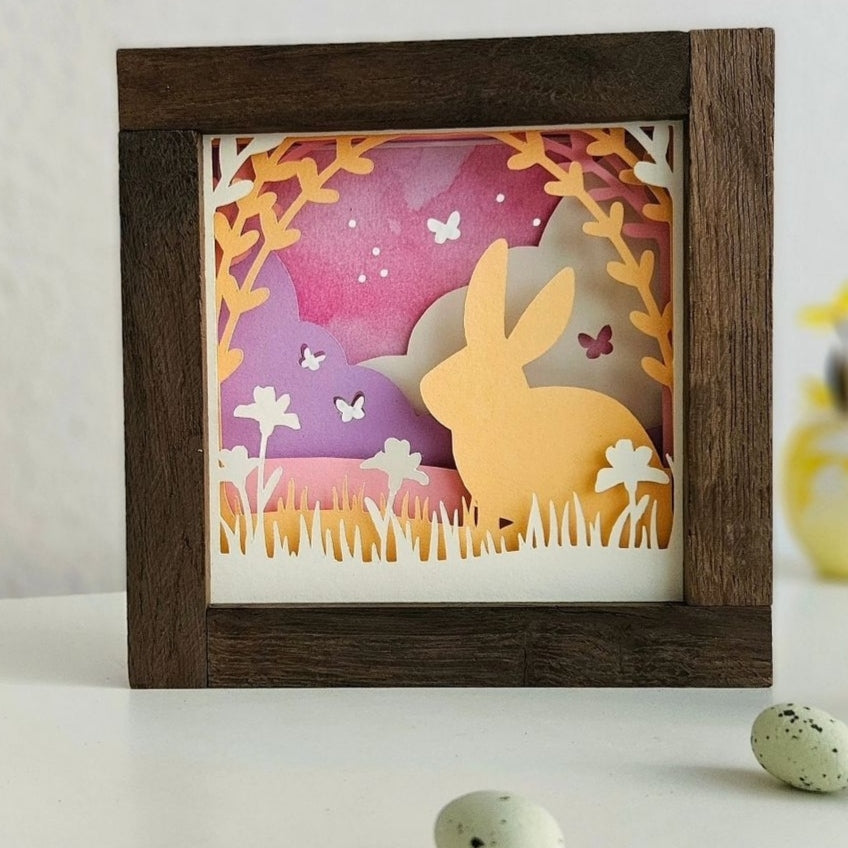 Bezauberndes Schattenbild eines Osterhasen, gestaltet mit der Osterhase Plotterdatei von easy-sticks. Die kunstvolle Gestaltung zeigt verschiedene Ebenen in zarten Farben, perfekt für festliche Osterdekoration.