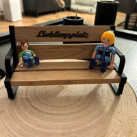 Miniaturbankhalter von easy-sticks mit zwei Spielzeugfiguren, die auf der Bank sitzen, perfekt für kreative Dekorationsideen.