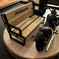 Detailaufnahme eines Bankhalters von easy-sticks mit einer Miniaturbank und einem Motorrad, schön platziert auf einem Holzuntergrund.