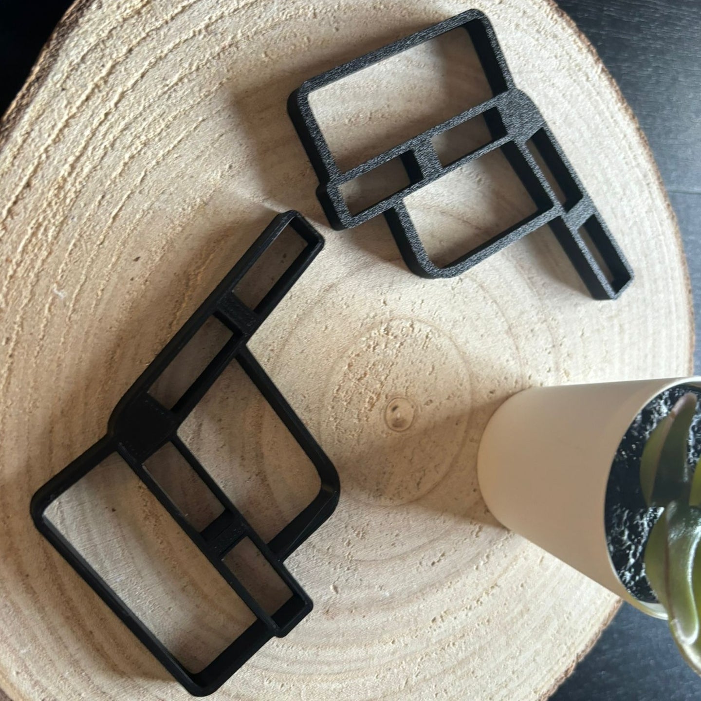 Zwei schwarze Bankhalter von easy-sticks, ideal zum Bau einer Miniaturbank, platziert auf einem natürlichen Holzuntergrund.