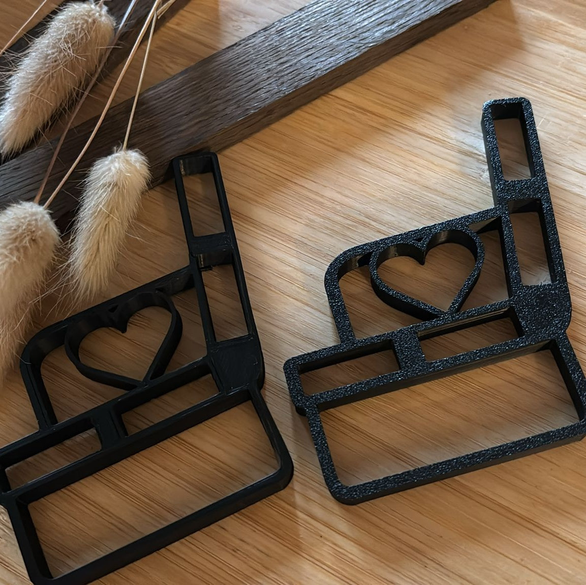 Zwei schwarze Bankhalter mit Herz von easy-sticks, wunderschön arrangiert auf einer Holzoberfläche neben Stil-Elementen, perfekt für kreative Bastelprojekte.