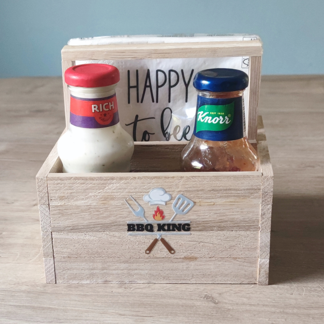 Holzbehälter mit BBQ King Aufkleber von easy-sticks, gefüllt mit Saucen, ideal für Grillpartys und BBQ-Events.