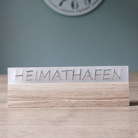 Acrylschild ohne Beleuchtung mit dem Schriftzug "HEIMATHAFEN" von Easy-Sticks, auf modernem Holzsockel platziert.