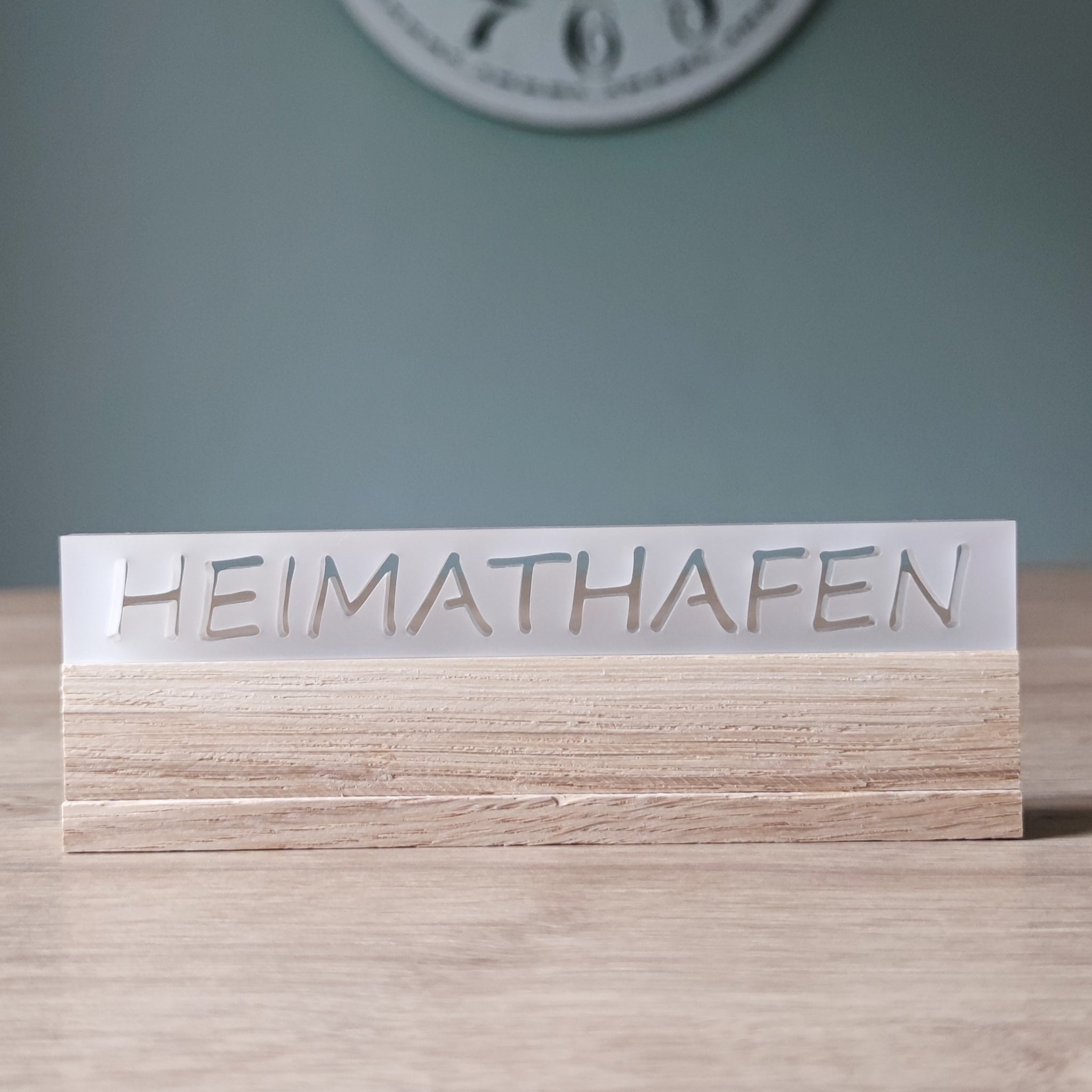 Acrylschild ohne Beleuchtung mit dem Schriftzug "HEIMATHAFEN" von Easy-Sticks, auf modernem Holzsockel platziert.