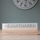 Stylisches Acrylschild mit dem Schriftzug "HEIMATHAFEN" von Easy-Sticks, auf einem Holzsockel, in zeitgemäßem Design.