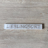 Nahaufnahme des Acrylsatzes "LIEBLINGSORT" von Easy-Sticks, der auf einer Holzoberfläche liegt.