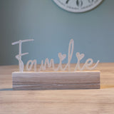 Rampe Schriftzug 'Familie' von Easy-Sticks in satinierter Ausführung, präsentiert auf einem stilvollen Holzsockel in einem gemütlichen Raum.