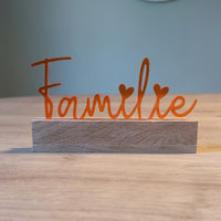 Acryl Aufsteller 'Familie' von Easy-Sticks in strahlendem Orange, dekorativ auf einem Holzsockel platziert und perfekt für das Wohnzimmer.