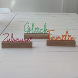 Dekorativer Acryl Aufsteller von Easy-Sticks mit dem Schriftzug 'Glück', umgeben von weiteren farbigen Wörtern, ideal für eine warme und einladende Atmosphäre.