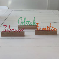 Dekorativer Acryl Aufsteller von Easy-Sticks mit dem Schriftzug 'Glück', umgeben von weiteren farbigen Wörtern, ideal für eine warme und einladende Atmosphäre.