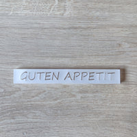 Minimalistisches Acrylschild von Easy-Sticks mit dem Text GUTEN APPETIT, stilvoll auf einem hellen Tisch platziert.