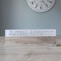 Elegantes Acrylschild von Easy-Sticks, beschriftet mit GUTEN APPETIT, platziert auf einem dekorativen Tisch.