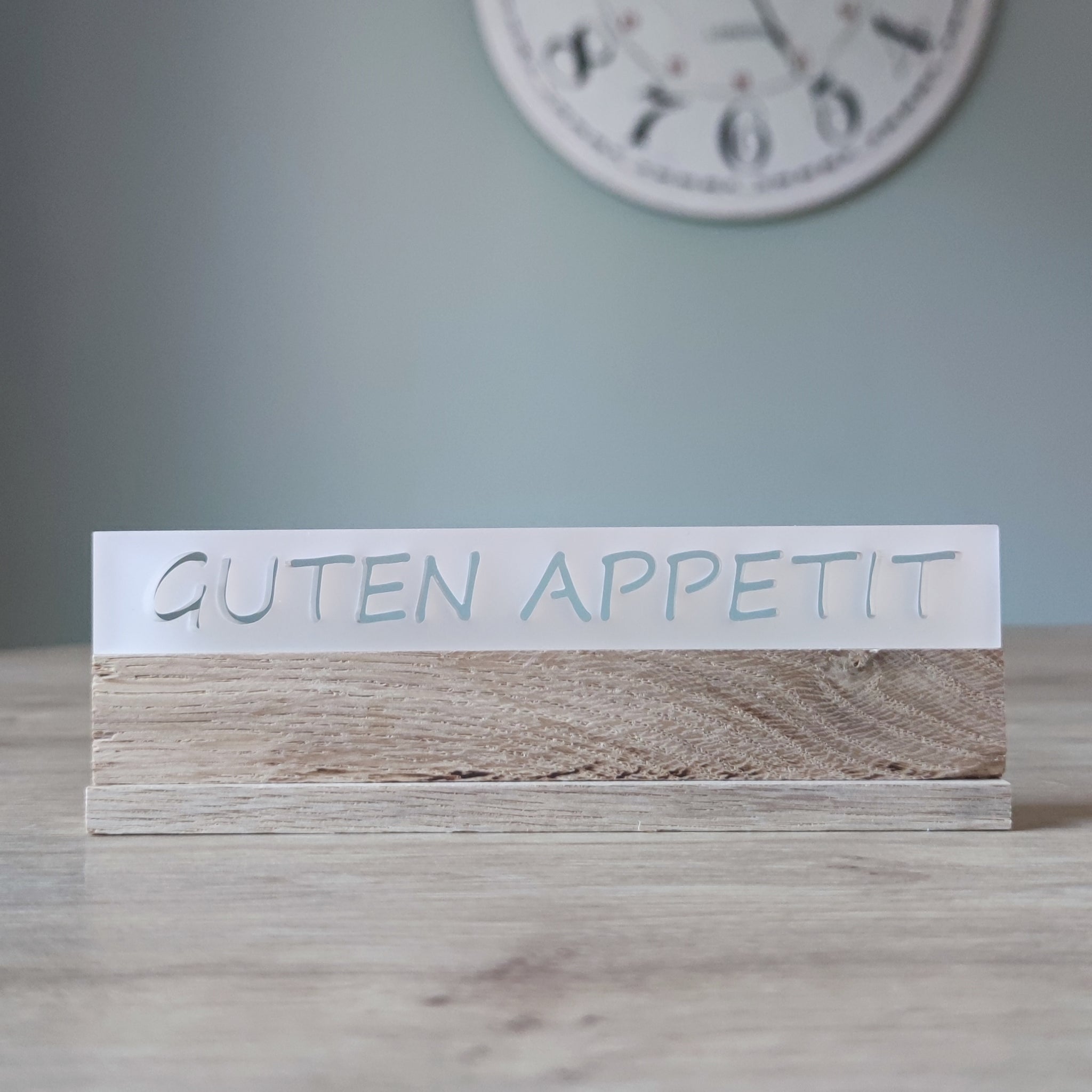 Elegantes Acrylschild von Easy-Sticks, beschriftet mit GUTEN APPETIT, platziert auf einem dekorativen Tisch.