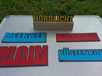 Schicke Plotter-Worte 'Nordlicht', 'Meerweh', 'Heimathafen', 'Moin' und 'Küstenkind' auf einem metallischen Untergrund, ein Design von easy-sticks.