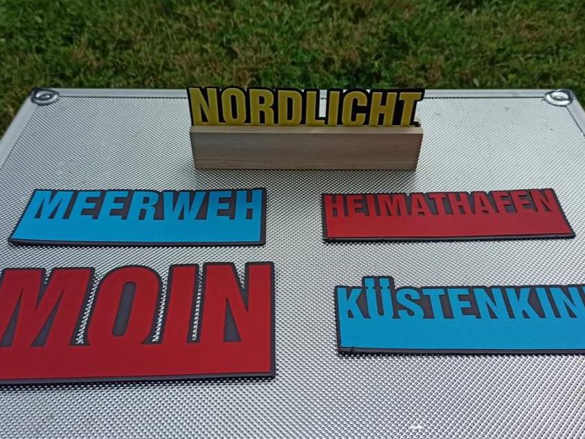Schicke Plotter-Worte 'Nordlicht', 'Meerweh', 'Heimathafen', 'Moin' und 'Küstenkind' auf einem metallischen Untergrund, ein Design von easy-sticks.