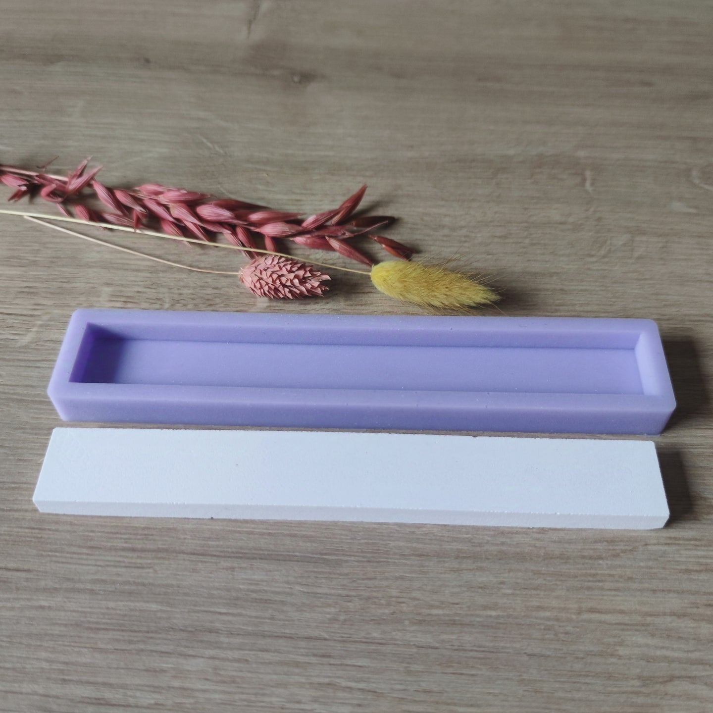 Easy-Sticks Silikonform - Schlicht - 16 cm Länge, lila Silikonform oben auf einer weißen Form, dekoriert mit Trockenblumen auf Holz.